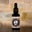 Photo of Charming Charlie’s Magical Beard Oil – Buck Naked  A beard oil bottle sits on a dark wood cabinet with a stone background.