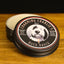 Photo of Charming Charlie’s Magical Beard Balm – Buck Naked  A beard balm tin sits on a wood cutting board 