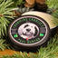 Photo of Charming Charlie’s Magical Beard Balm – Paul Bunyan  A beard balm tin sits on a wood cutting board surrounded by pine, spruce and various pinecones.